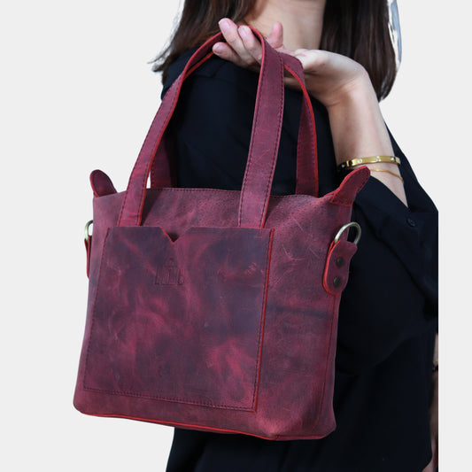 Small Leather Tote Bag in hands of model posing placing it at her shoulder