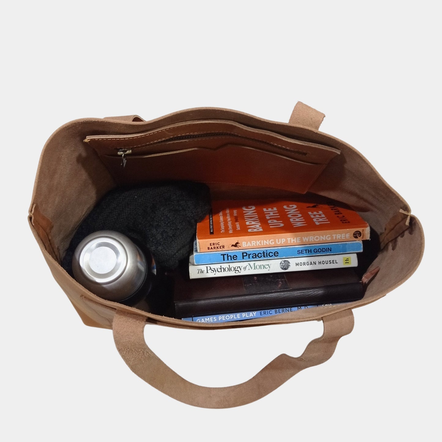 Fully loaded Matilda brown leather tote sorting books, water bottle, and woolen cap