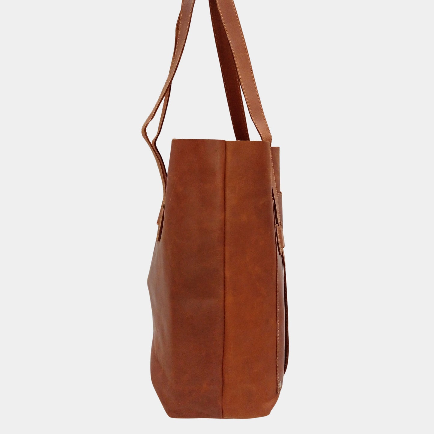 Side view of Brown Leather Tote with dual lined large shoulder straps