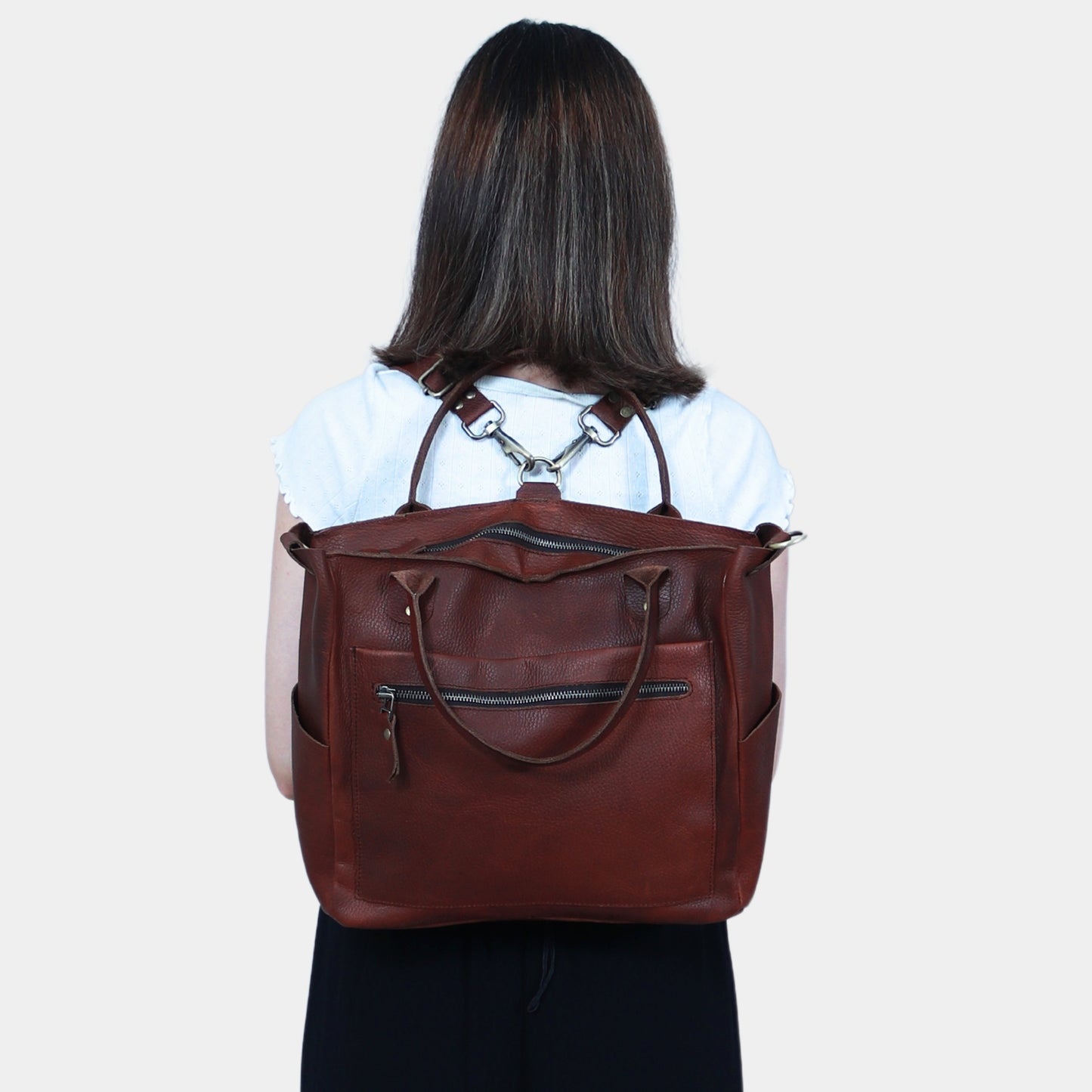 woman in black and white dress wearing Bella Leather Tote as backpack using removable leather straps 