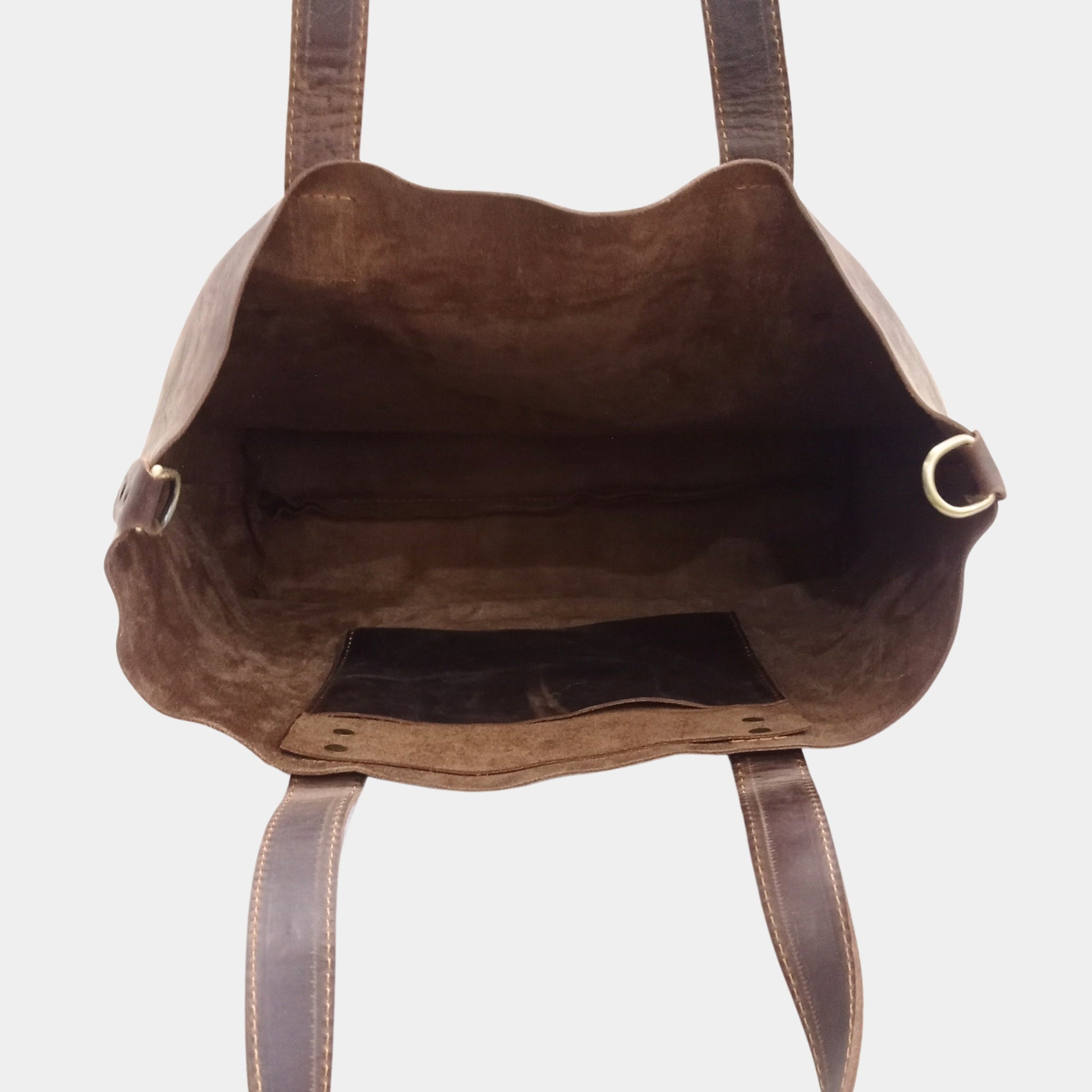 Unlined Interior of leather tote showing side sling pocket vintage brass hooks for removable strap attachment