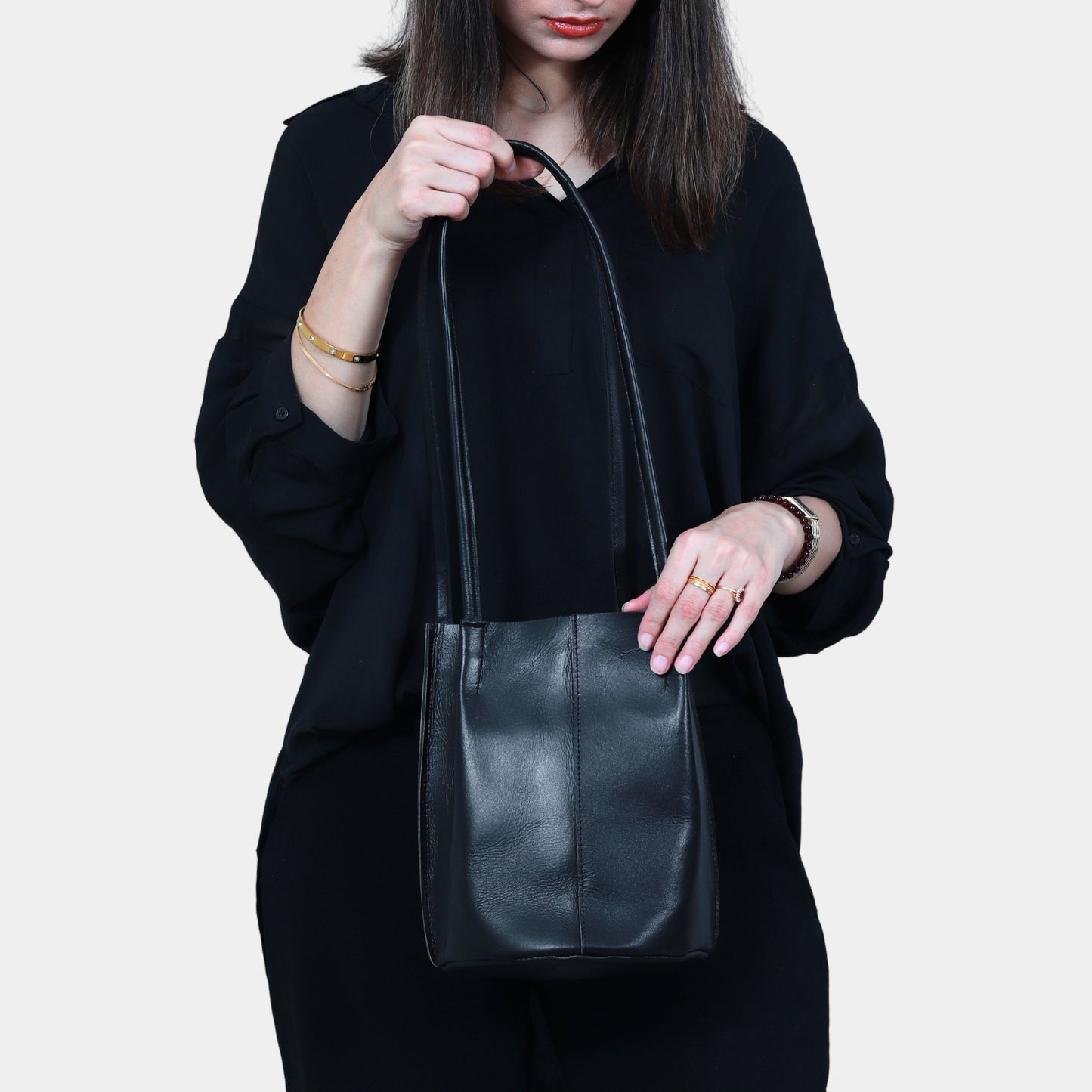 Teenage Girl in black dress Elegantly holding sleek black leather tote bag in her hands