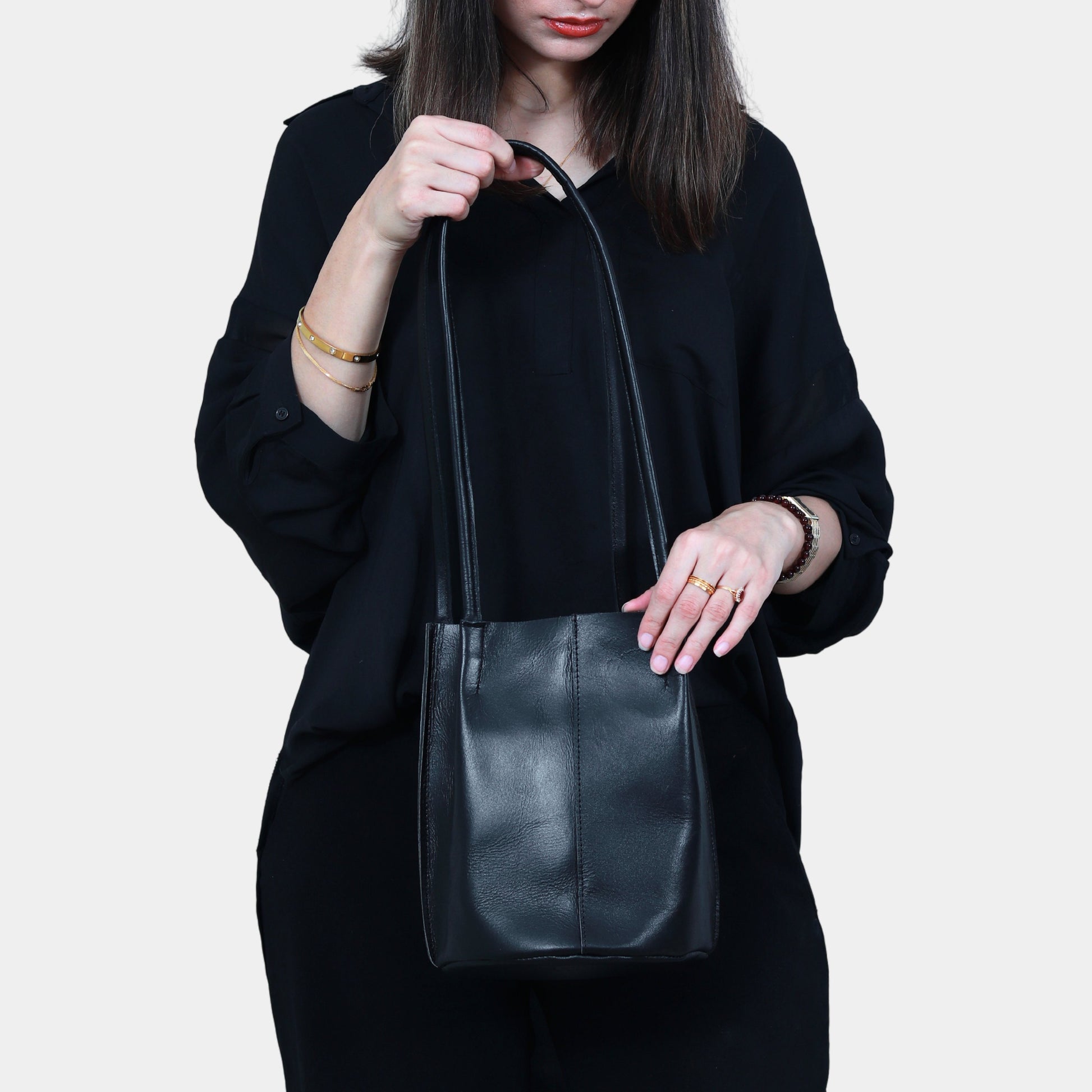 Teenage Girl in black dress Elegantly holding sleek black leather tote bag in her hands