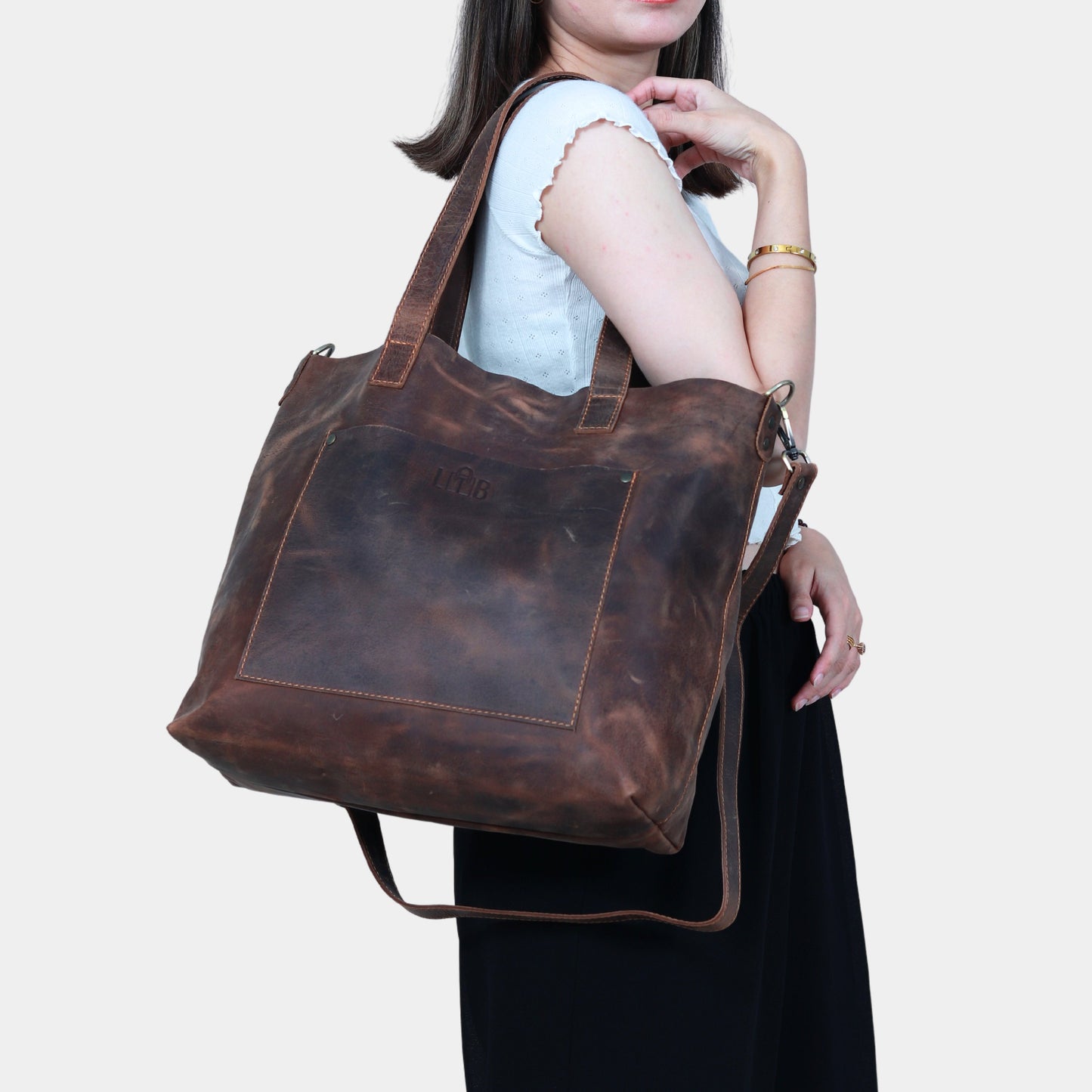 Teenage girl in white shirt elegantly carrying large brown work tote with durable removable straps 