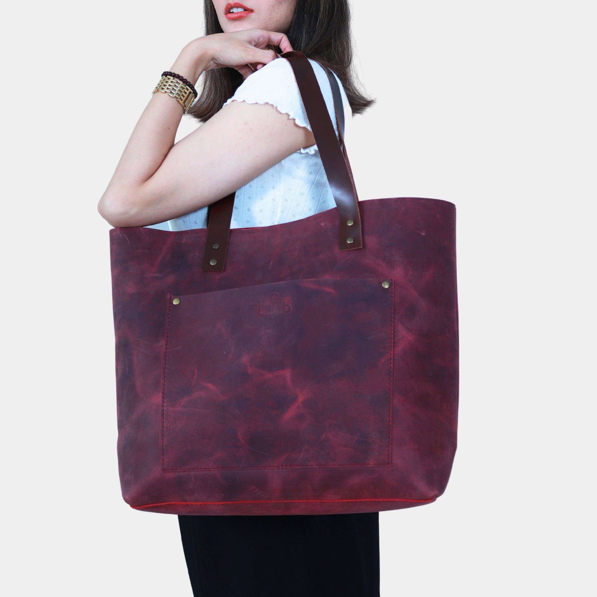 A woman with white shirt slinging Lily Leather Tote at her shoulder and posing confidently 