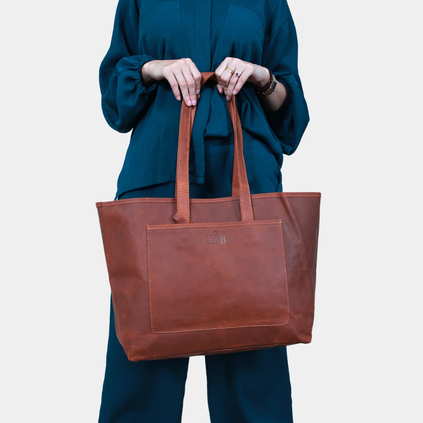 A girl in green dress holding Mila Brown Leather Tote elegantly in her hands