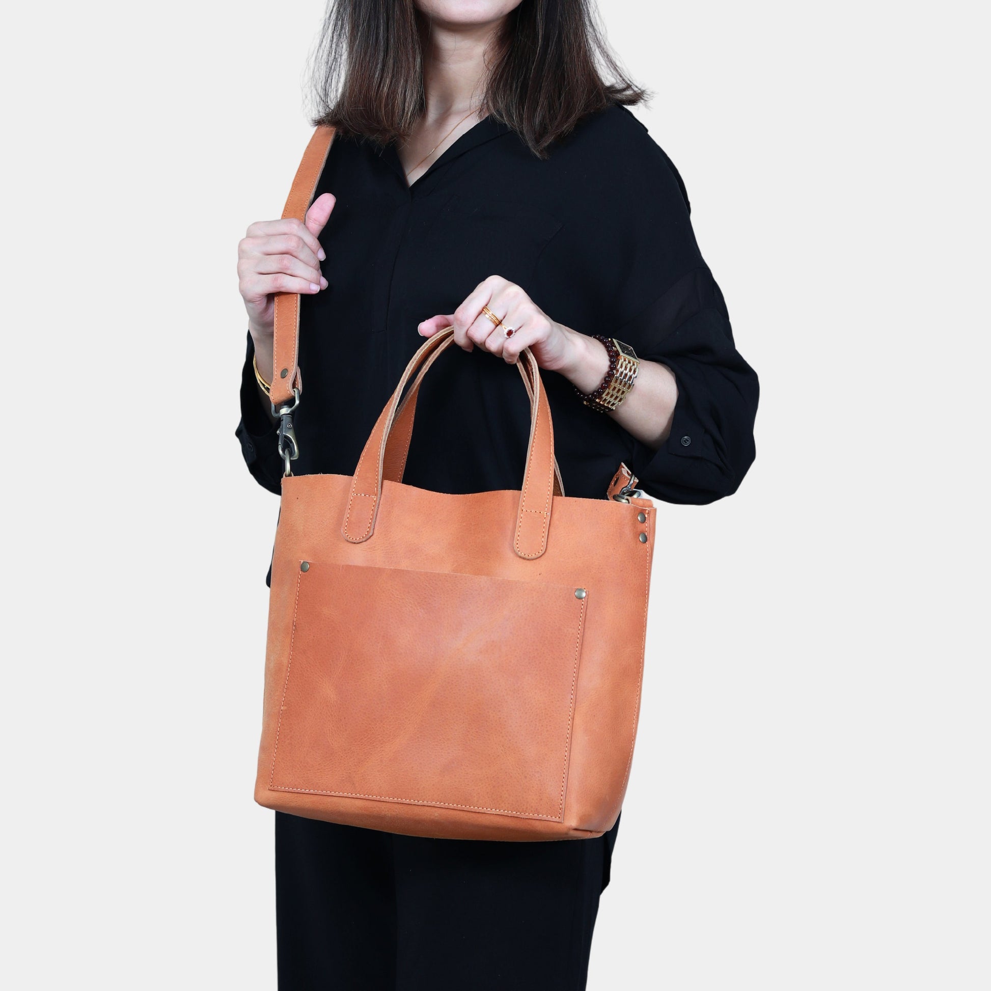 Woman in Black dress posing with Brown Leather Tote wearing cross body garbing handles