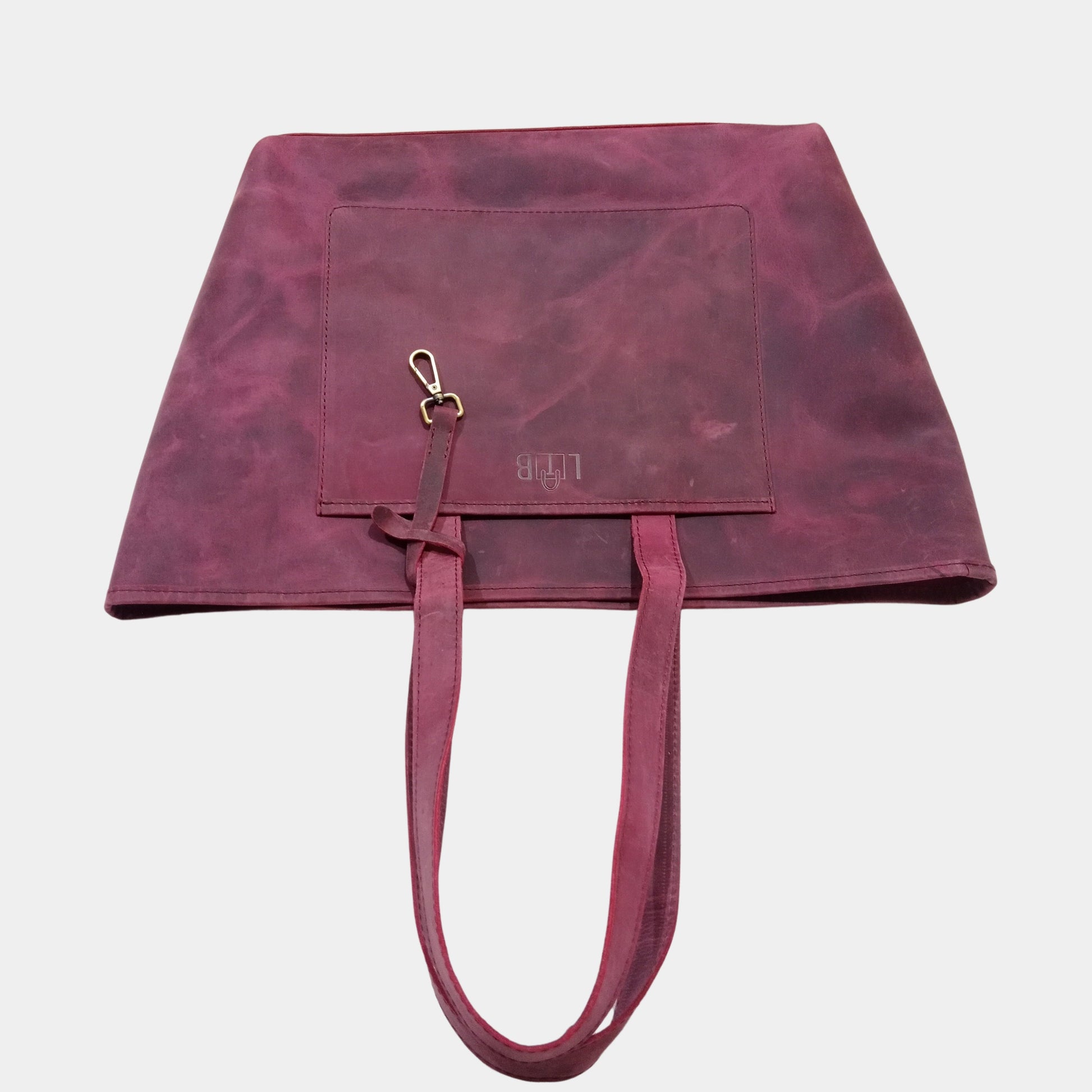 Large office Leather Tote laying on table showing profile of bag featuring vintage brass accessory strap 