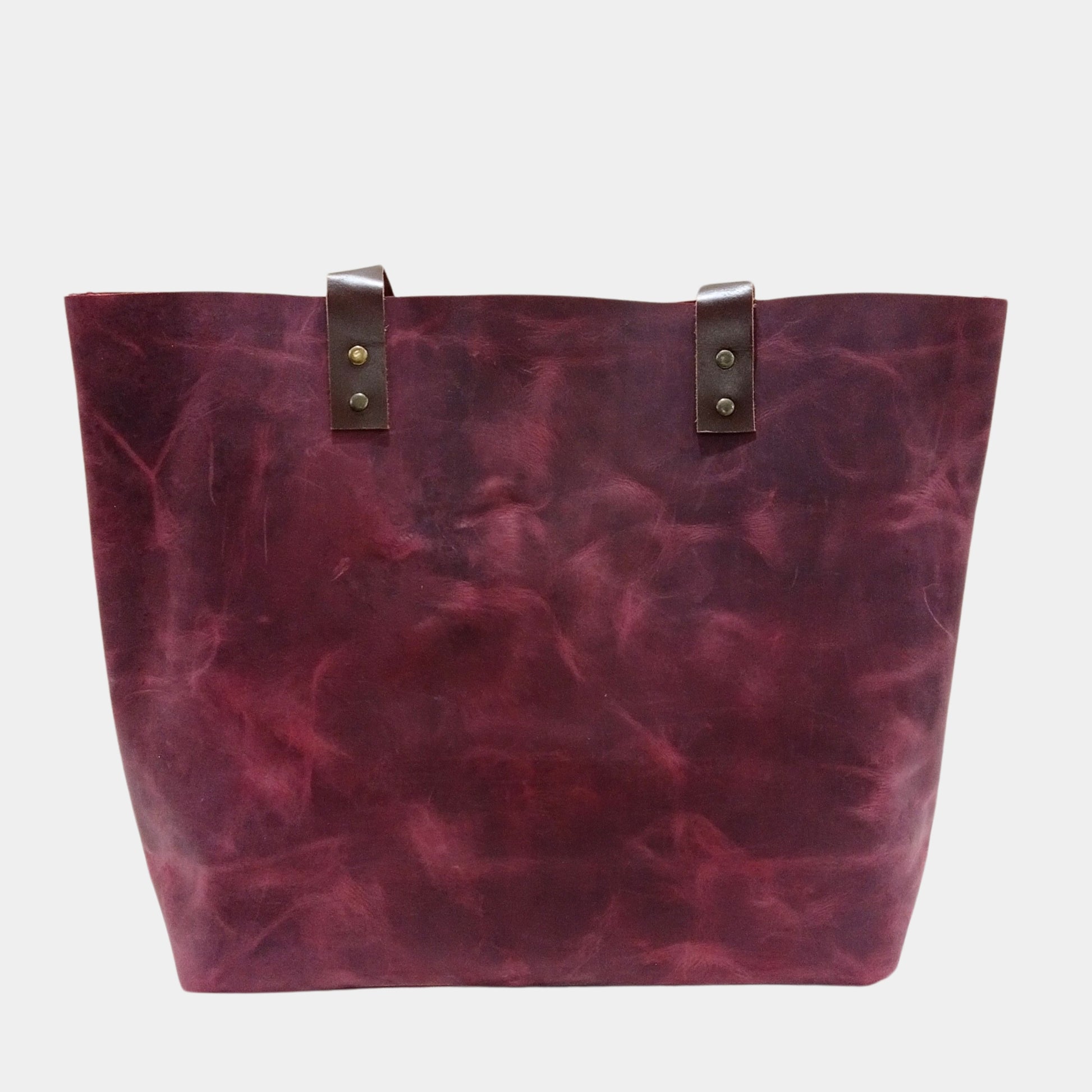 Back side of stylish burgundy leather tote bag with soft brown leather handles