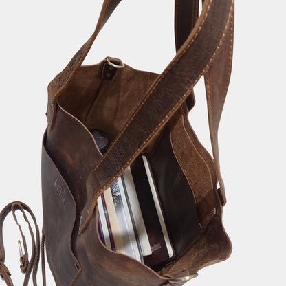 Grace Leather Tote in brown showing interior having books while removable strap lying beside bag