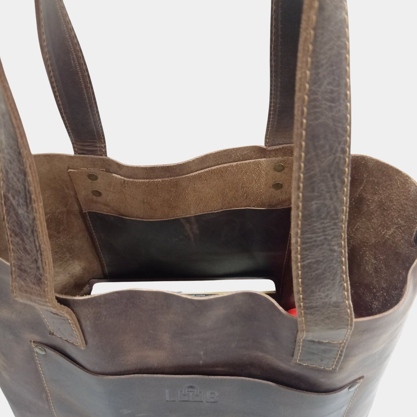 Side slinging pocket inside brown leather tote bag and unlined soft interior